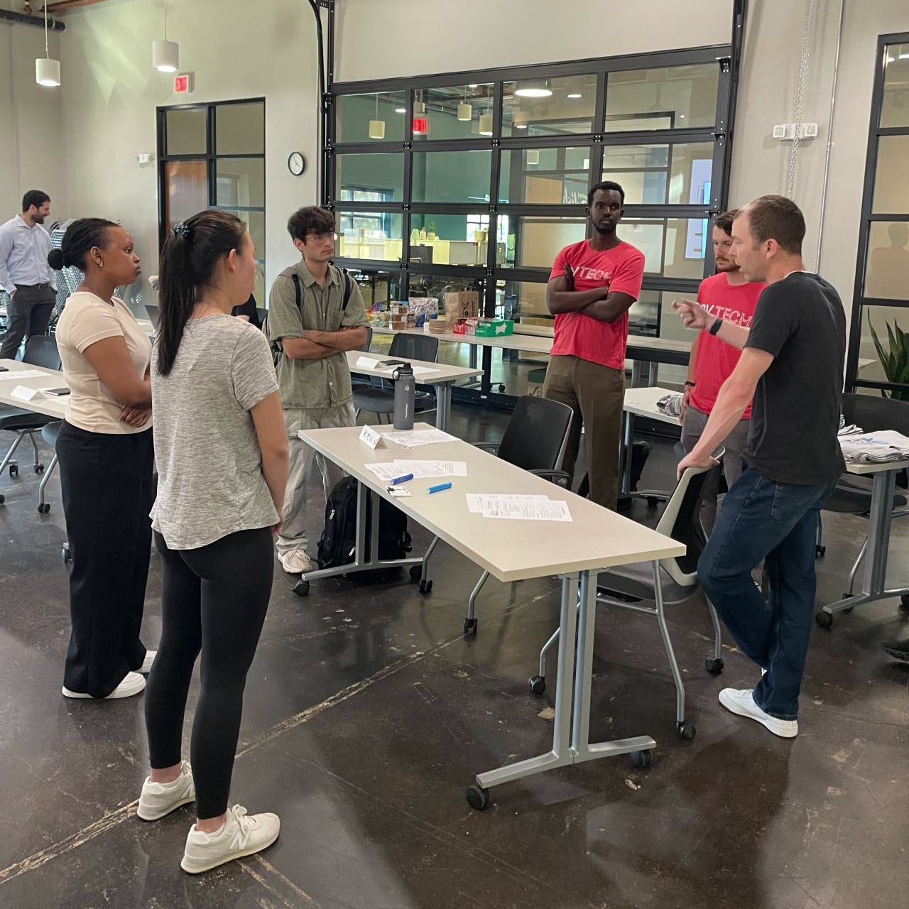 A group of people standing in a circle while one of them talks and gestures